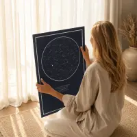 A woman sitting by a window looking at a personalised navy star map poster